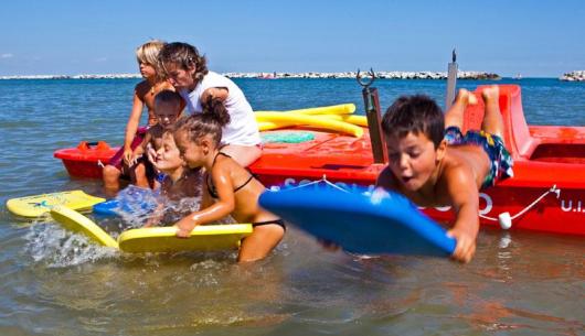 Bambini giocano in mare con tavole da surf.