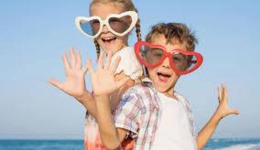 Bambini felici con occhiali a cuore in spiaggia.