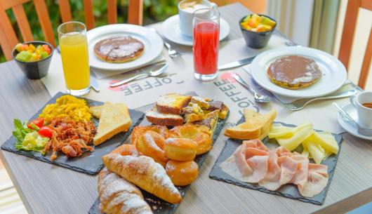 Colazione variegata con dolci, salumi e bevande.